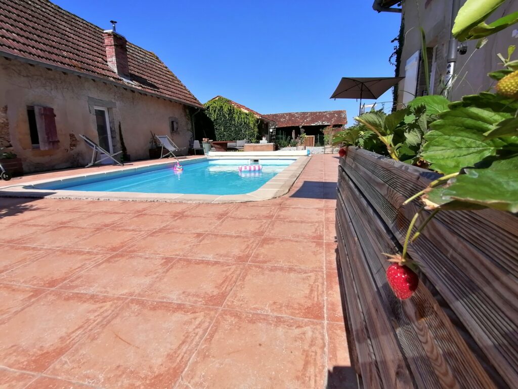 Piscine commune et terrasse ensoleillée avec chaises longues et parasols dans un cadre relaxant