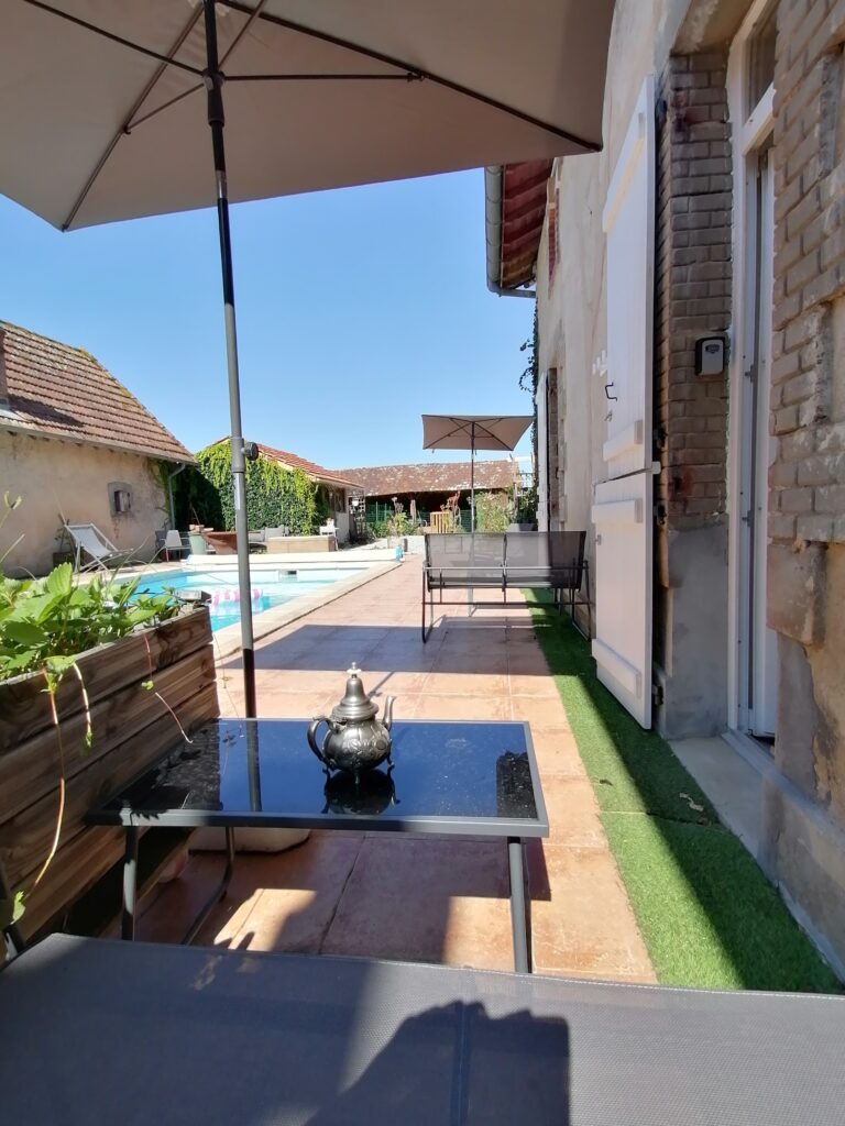 Piscine commune et terrasse ensoleillée avec chaises longues et parasols dans un cadre relaxant